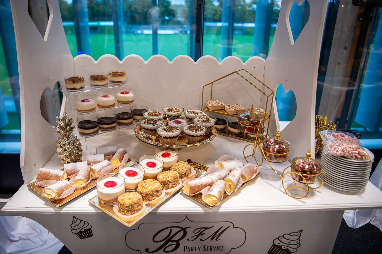 Colț dulce aranjat elegant la nuntă, cu prăjituri, macarons și bomboane colorate