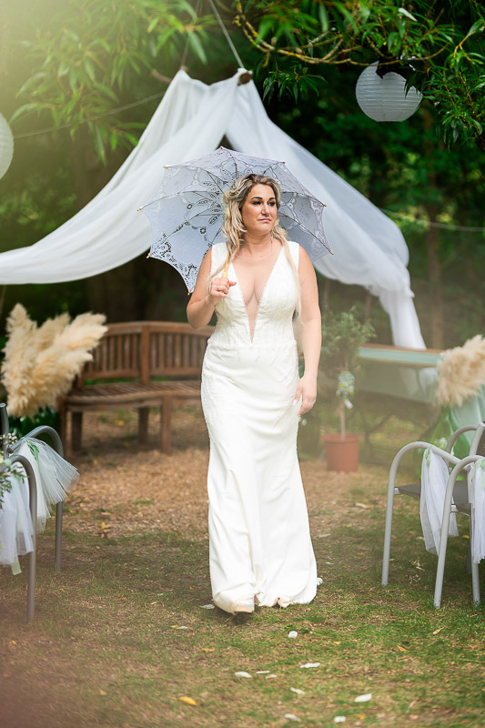 Portret de mireasă cu o umbrelă din dantelă într-un decor natural, surprins de un fotograf nuntă București.
